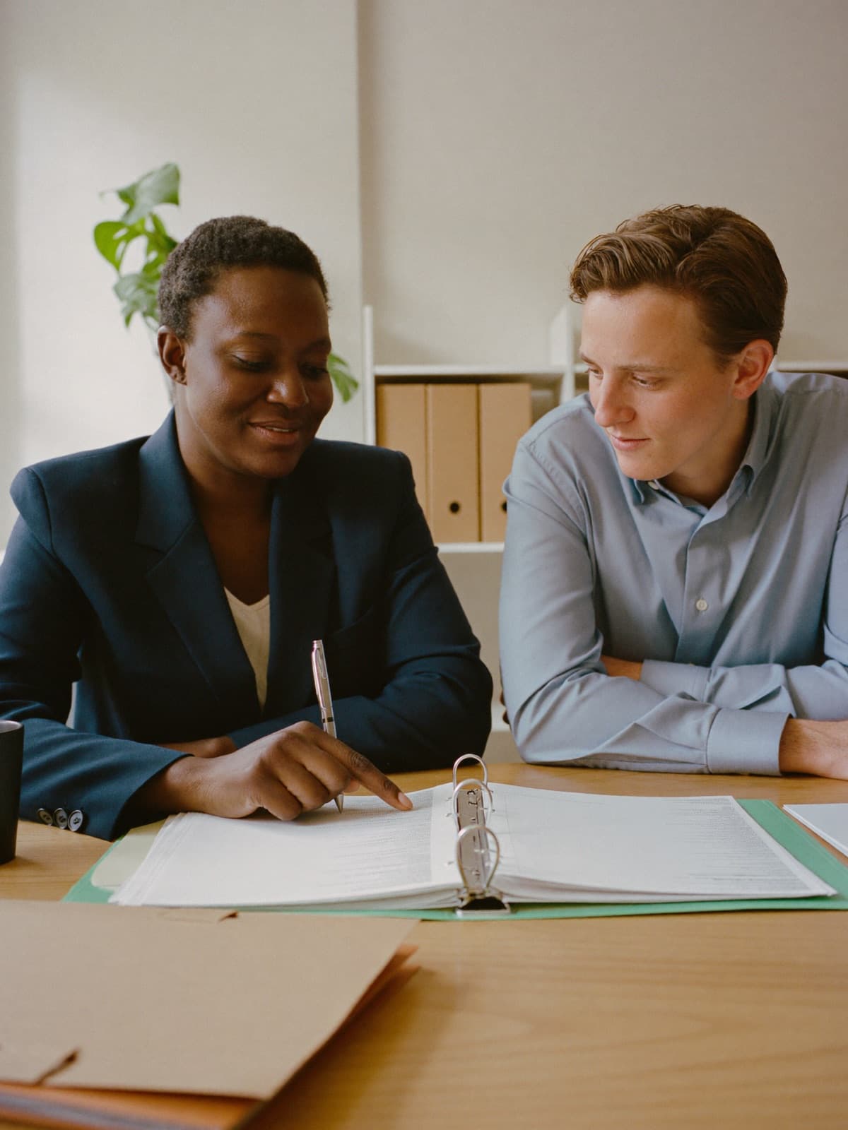 A business owner and a colleague at a table, working through a checklist in a ring binder together